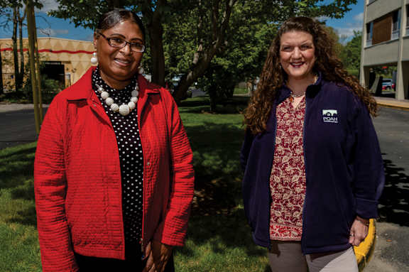 Two women standing outside on a sunny day.