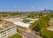 Thumbnail 55 of 59 - A cityscape with a mix of modern and older buildings, a large open area with trees, and a clear sky.