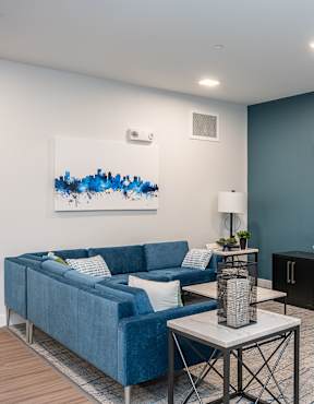 A living room with a blue couch, a coffee table, and a TV mounted on the wall.