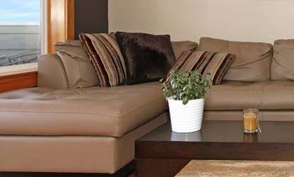 A living room with a brown sofa and a glass table.