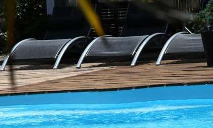 A pool surrounded by lounge chairs and plants.