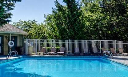 A pool surrounded by a white fence and trees. at Commons at Avalon Park Apartments, Tigard, Oregon