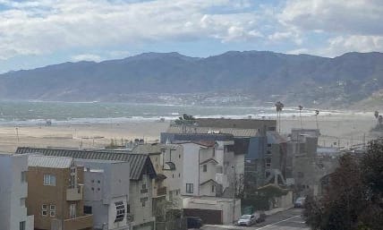 a view of the beach and the mountains in the distance from a town