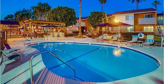 A swimming pool with lounge chairs and a building in the background.