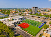 Thumbnail 51 of 59 - A red and green baseball field in the middle of a city.