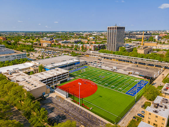 A red and green baseball field in the middle of a city.