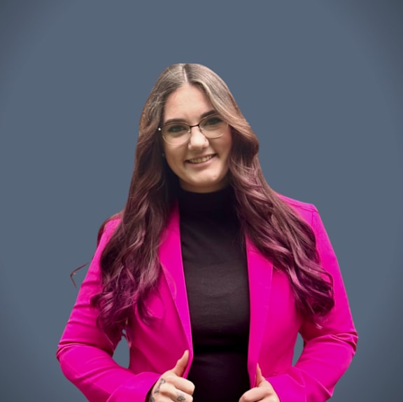 A woman with purple hair wearing a plaid blazer.
