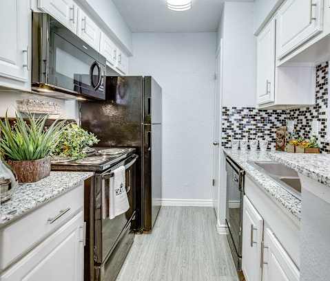 A kitchen with a black refrigerator and white cabinets.