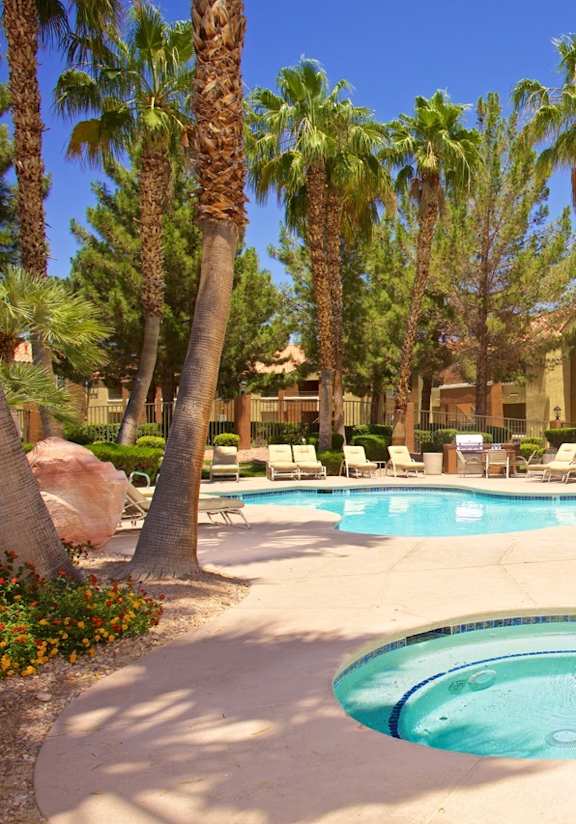 A swimming pool surrounded by palm trees and lounge chairs.