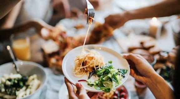 A person is serving a plate of food to another person at a table.