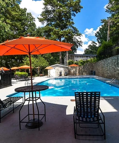 a patio with chairs and an umbrella next to a swimming pool at Tucker Square, Stone Mountain, GA