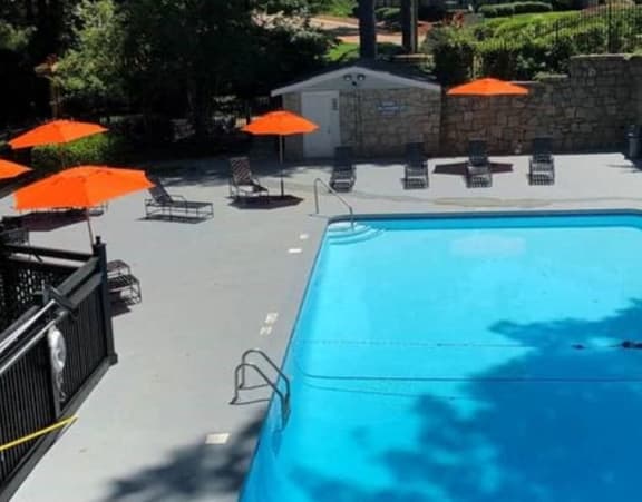 a swimming pool with orange umbrellas and chairs around it at Tucker Square, Georgia