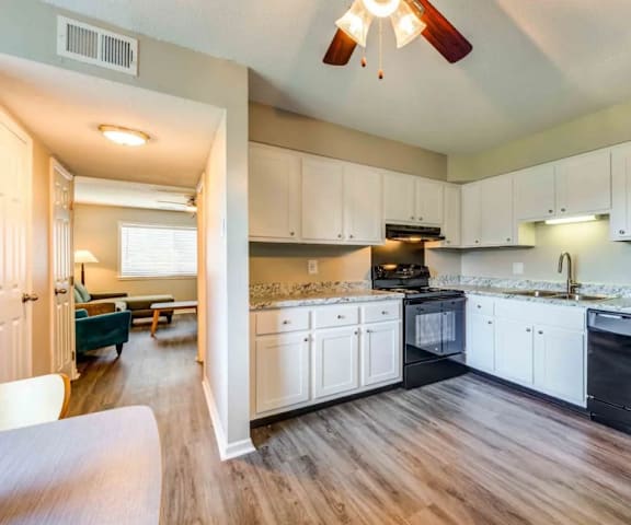 A kitchen with white cabinets and a black refrigerator.