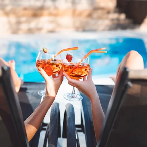 Two people toasting with drinks in their hands.