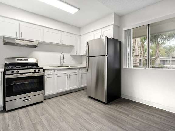 A kitchen with a table and chairs in front of a fridge and cabinets.