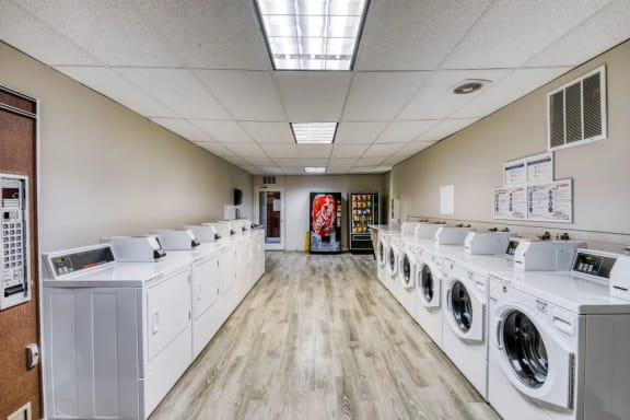 a washer and dryer room with a row of washers and washing machines