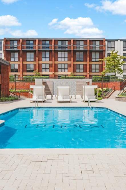 a pool with chairs and umbrellas in front of an apartment building at Up House, Farmington, Connecticut