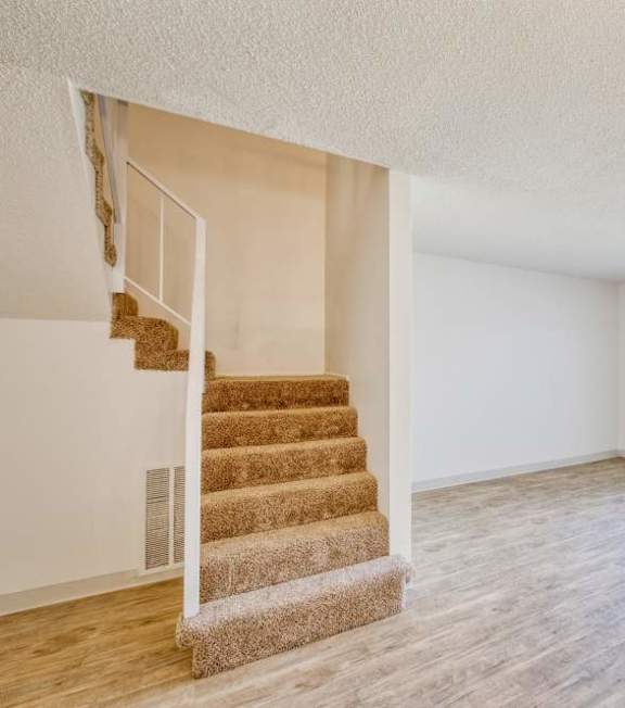 A room with a staircase and sliding glass doors.