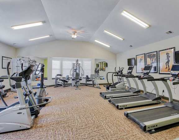 a gym with cardio machines and televisions