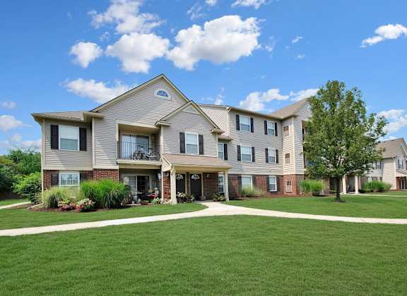 A large, modern house with a well-manicured lawn in front.