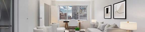 A modern living room with a grey sofa, a coffee table, and a large window at The Caldwell Apartments, New York, 10028