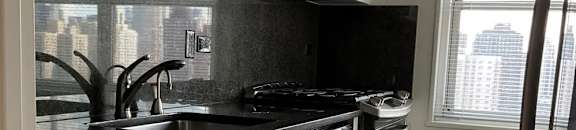 A kitchen with black countertops and white cabinets at The Caldwell Apartments, New York, 10028