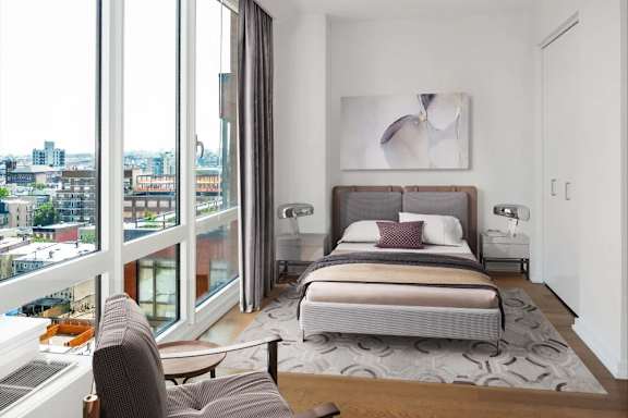 A bedroom with a large bed and a view of the city at The Maximilian Apartments, New York