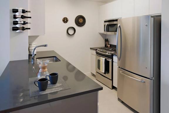 A kitchen with a stainless steel refrigerator and oven at The Maximilian Apartments, Long Island City, NY, 11101