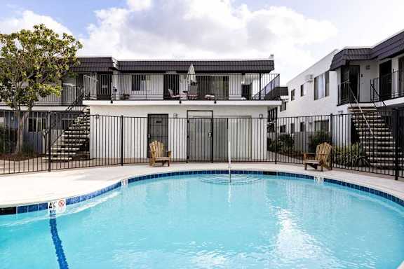 A swimming pool in front of a white building with a black fence.