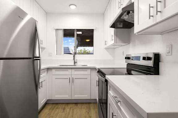 A modern kitchen with white cabinets and stainless steel appliances.