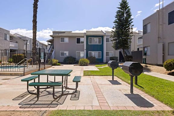 A green picnic table is in the middle of a courtyard.