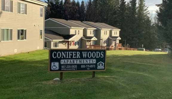 a sign apartments in front of some houses at Conifer Woods Apartments, Alaska
