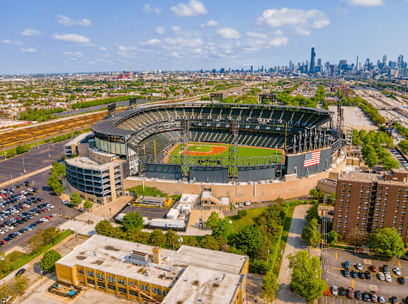 A large stadium with a green field in the center and a city skyline in the background.