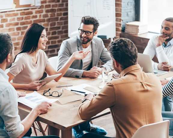 A group of people are gathered around a table in a meeting.