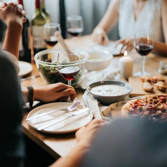 a group of people sitting around a table eating food and drinking wine
