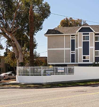 A row of townhouses with a white fence in front.