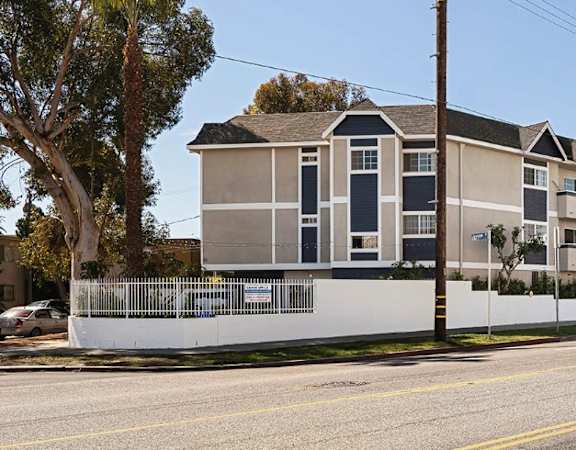 A row of townhouses with a white fence in front.