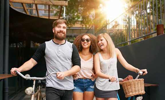 a man and two women walking their bikes down a sidewalk