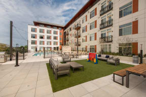 Outdoor lounge area with lounge chairs and tables on a lawn at Highgate At The Mile Apartments