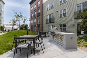 outdoor seating, dining tables and a gas grill for residents