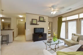 Hendersonville Apartments for Rent -The Grove at Waterford Crossing Living Room with Stylish Decor, Wall to Wall Carpet, Ceiling Fan, Window, and Access to Dining Area and Hallway