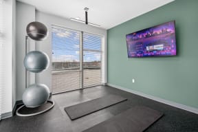 a yoga room with a large screen tv and exercise equipment