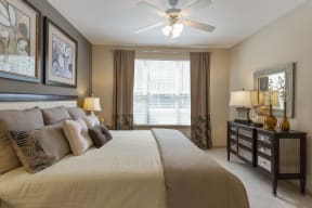 The Grove at Waterford Crossing Apartments in Hendersonville - Bedroom with Stylish Decor, Wall to Wall Carpet, Green and White and Grey Walls, Ceiling Fan, and Access to Bathroom