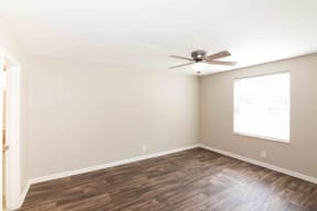 Apartments for Rent Murfreesboro - Condos at the Villager - Spacious Bedroom With Wood Flooring, a Ceiling Fan, Window With Blinds, and Access to the Bathroom