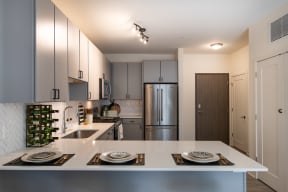 Spacious Kitchen with Sleek Gray Cabinets, Stainless Steel Appliances, and Sparkling White Counters