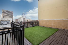 a small astroturf lawn on a balcony with a city in the background