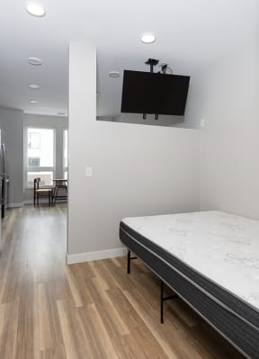 a bedroom with a bed and a tv on the wall