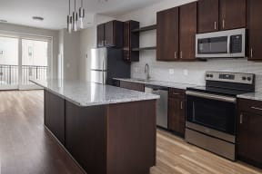 a kitchen with dark wood cabinets and an island with a granite countertop and stainless steel appliances