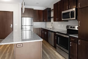 a kitchen with dark wood cabinets and stainless steel appliances