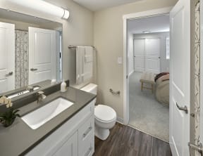 Ensuite bathroom with hard wood style flooring, toilet and vanity sink.